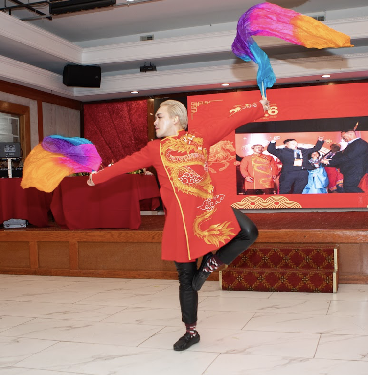 Minh Nguyen performing The Fire Horse in a red costume with colorful silk fans